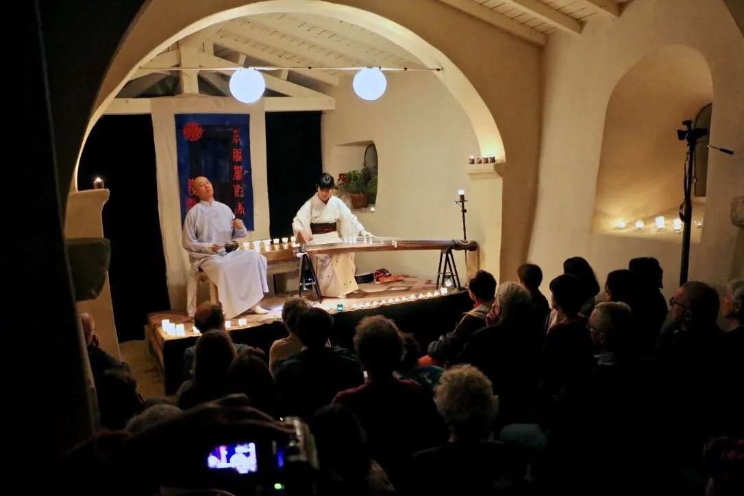 Two musicians performing in a vaulted exhibition space