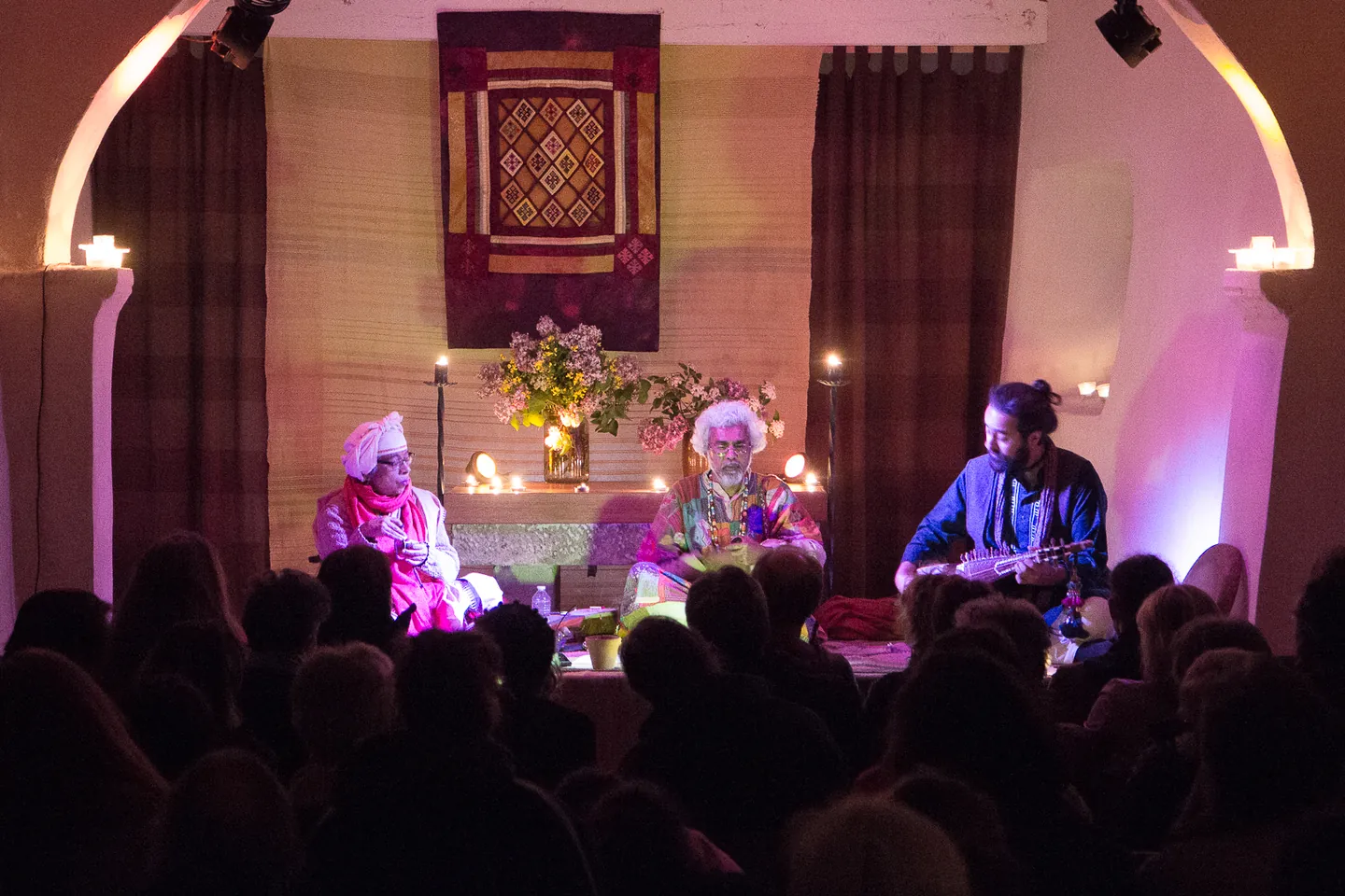 Three seated musicians performing in front of an audience