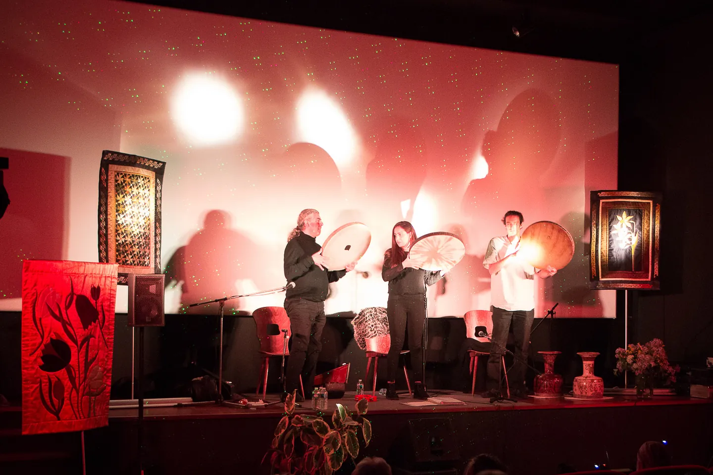 Three musicians with frame drums among textile works