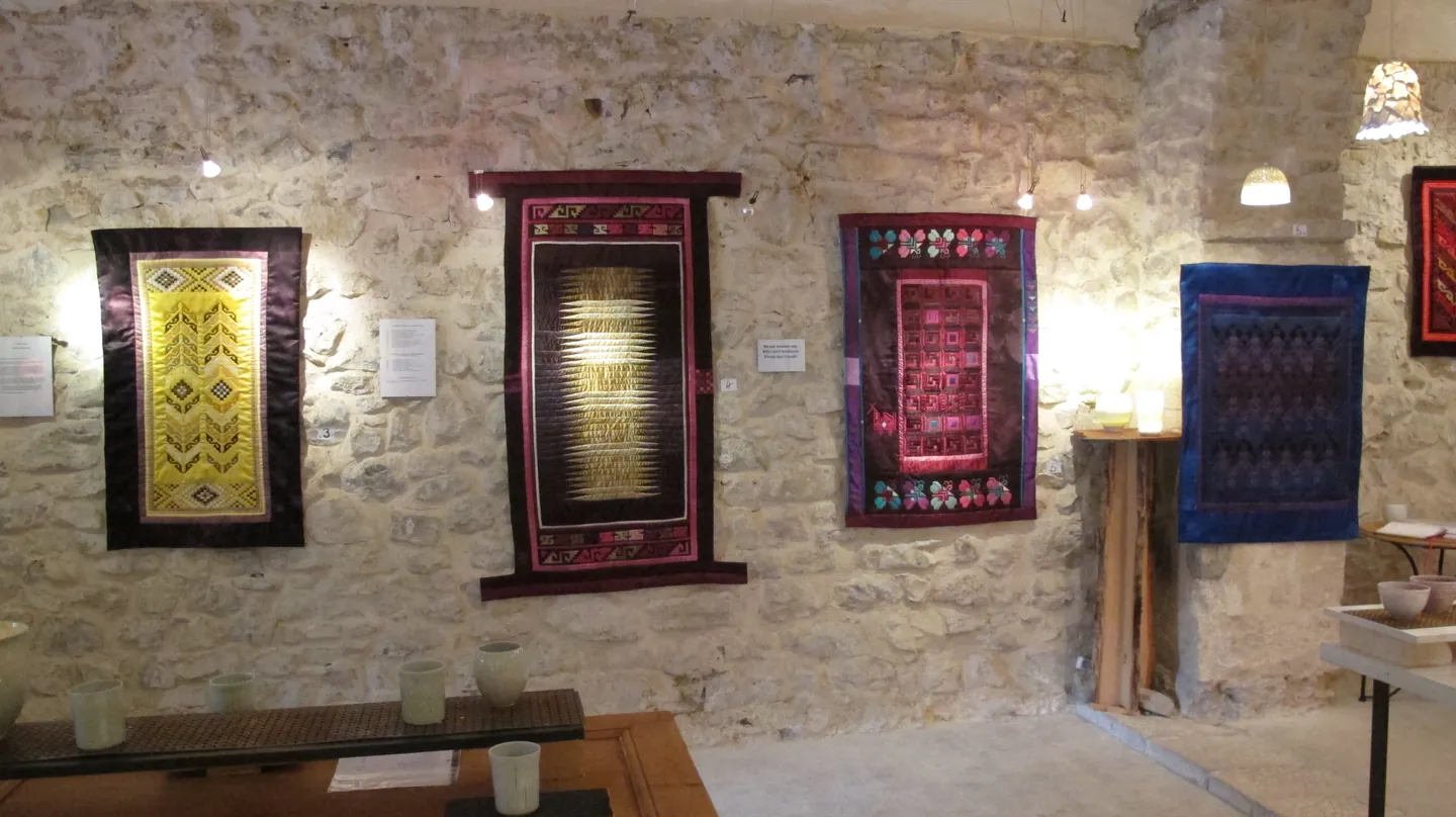 Textile works and ceramics in a stone-walled gallery