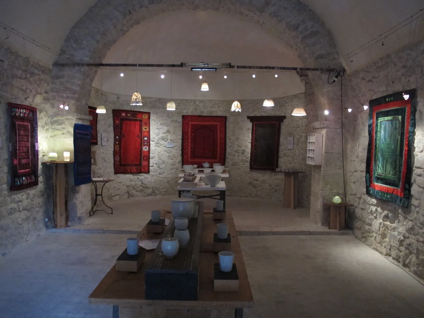 Wide view of an exhibition of textile works and ceramics